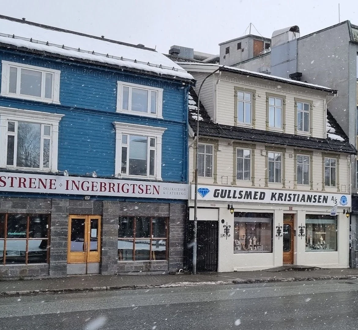 Gullsmed Kristiansens hvite trehus i Kirkegata, med skiltet over butikkvinduene, mens snøen laver ned